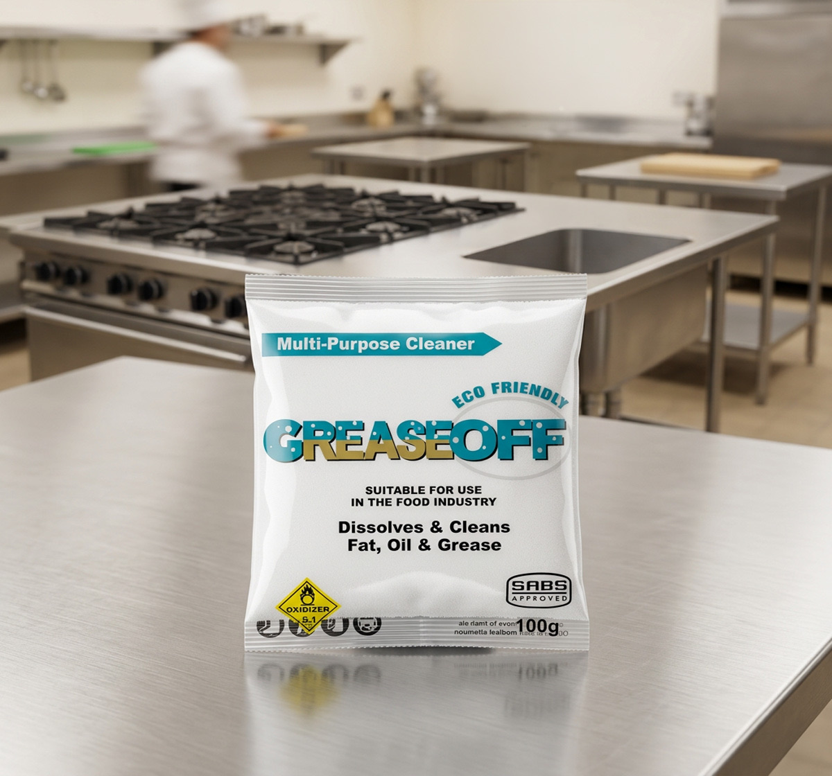 GreaseOff 100g sachet on a stainless steel prep counter in a commercial kitchen